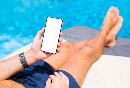 Man using mobile phone while relaxing by the poolの写真素材