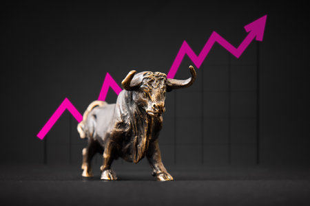 Bronze bull figurine in front of a graph with an arrow indicating uptrend in business and marketsの写真素材