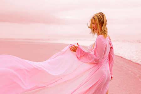 Woman in pink dress on the beachの写真素材