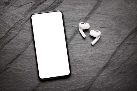 Mockup of modern mobile phone with empty screen and wireless earphonesの写真素材