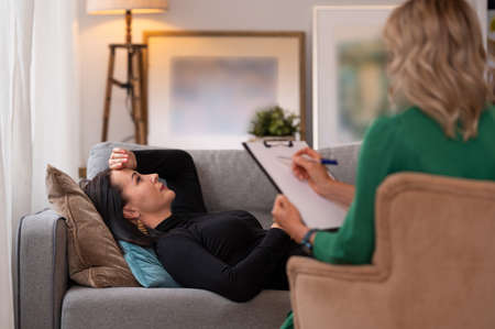 Woman lying in couch during therapy sessionの写真素材