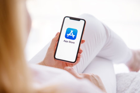 Riga, Latvia - March 26, 2021: Woman holding mobile phone with App Store logo on the screenのeditorial素材