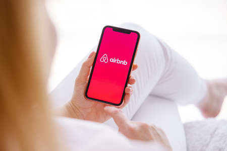 Riga, Latvia - March 26, 2021: Woman holding mobile phone with Airbnb logo on the screenのeditorial素材