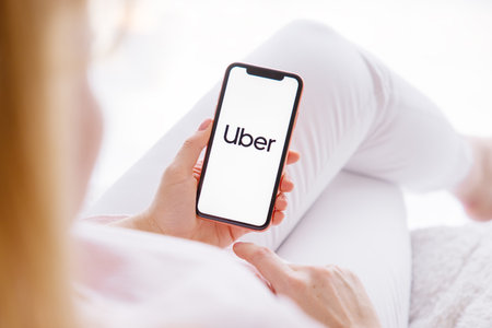 Riga, Latvia - March 26, 2021: Woman holding mobile phone with Uber logo on screenのeditorial素材