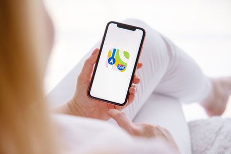Riga, Latvia - March 26, 2021: Woman holding mobile phone with Maps icon on screenのeditorial素材