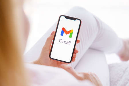 Riga, Latvia - March 26, 2021: Woman holding mobile phone with Gmail logo on the screenのeditorial素材
