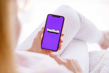 Riga, Latvia - March 26, 2021: Woman holding phone with Twitch logo on the screenのeditorial素材