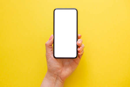 Mobile phone with empty screen in hand on yellow backgroundの写真素材