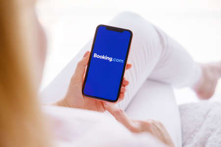 Riga, Latvia - March 26, 2021: Woman holding mobile phone with Booking.com logo on the screenのeditorial素材