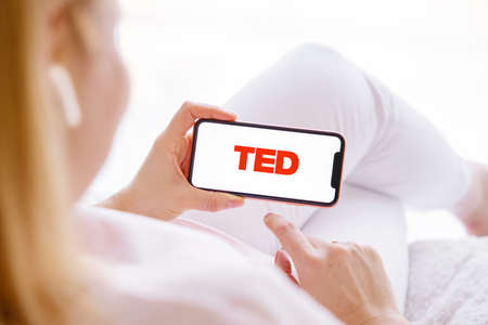 Riga, Latvia - March 26, 2021: Woman holding phone with TED logo on the screenのeditorial素材