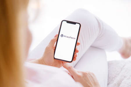 Riga, Latvia - March 26, 2021: Woman holding mobile phone with WordPress logo on the screenのeditorial素材