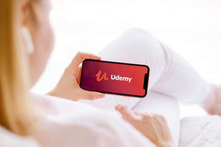 Riga, Latvia - March 26, 2021: Woman holding mobile phone with Udemy  logo on the screenのeditorial素材