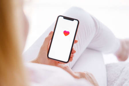 Riga, Latvia - March 26, 2021: Woman holding mobile phone with Health app icon on the screenのeditorial素材