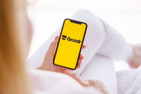 Riga, Latvia - March 26, 2021: Woman holding mobile phone with Grindr logo on the screenのeditorial素材