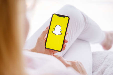 Riga, Latvia - March 26, 2021: Woman holding phone with Snapchat logo on the screenのeditorial素材