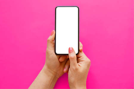 Mobile phone with empty white screen in hands on pink backgroundの写真素材