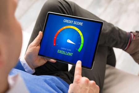 Man looking at his credit score test on tablet computer showing excellent scoreの写真素材