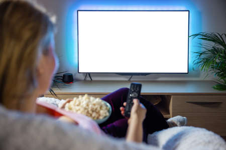 Woman watching TV with empty white screenの写真素材