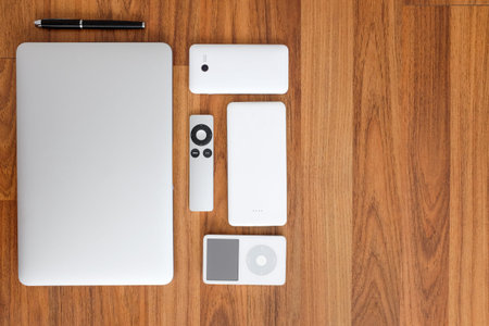 Top view flat layout of laptop computer close with smartphone, remote, mouse, speaker, portable music player & battery pack. On wood top. Have space on the right for Copy writing or text.の写真素材