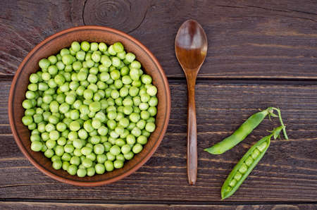 Green peas in a clay bowl on a wooden backgroundの写真素材