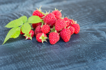 Red fresh raspberries on rustic wood background. natural ripe organic berries with green leaves