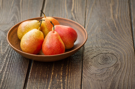 Pears. Collecting pears. Fresh ripe pears in a clay plate on a wooden table. Pear autumn harvest....