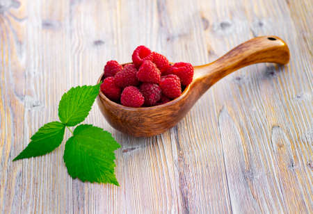 Raspberries in a wooden dipper. Raspberry berries on wooden background. Raspberry berries closeup.の写真素材