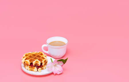 A cup of coffee with milk and homemade waffles on a pink background. Tasty breakfast. Minimalism.の写真素材