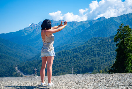 Young girl blogger making selfie on smartphone camera against a background of mountain scenery