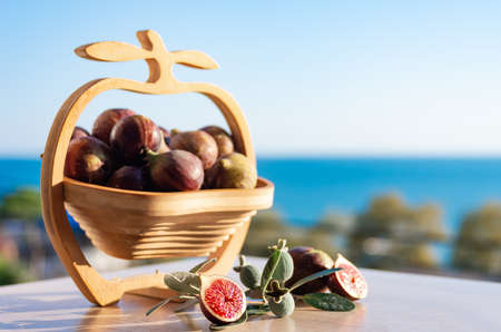 Fresh figs. Fig fruits in a wooden vase against the background of the sea. Summer harvest. Free space for textの写真素材