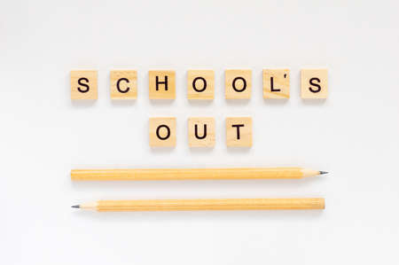 School's out. The inscription in wooden letters on a white background. Pencils on a white backgroundの写真素材