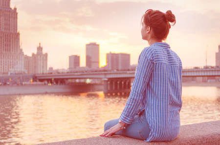 A young girl on the background of the cityscape looks thoughtfully into the distance. Toning.の写真素材