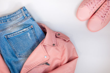 Flat composition with a set of clothes in pink colors. Top view of clothes on a white background....