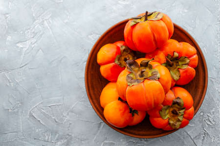 Orange ripe persimmon fruits on a light background. Background with copy space, place for text, top viewの写真素材