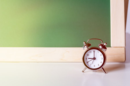 Back to school. Alarm clock on the background of the school board. Arrows showing 9am. School...