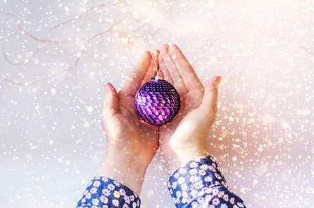 Closeup of a young girls hands holding a christmas ball. Shiny sequins on a Christmas ball.の写真素材