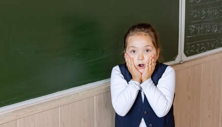 A first grader stands at the blackboard and is very scared. Back to school.の写真素材