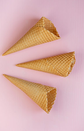 Three empty waffle cones on a pink background. Flat lay. Minimalism.