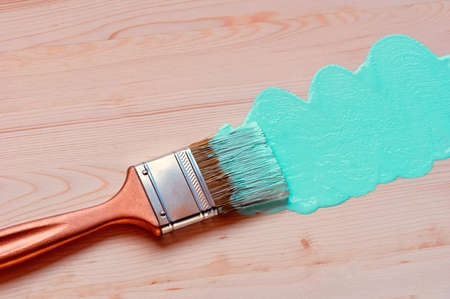 Paintbrush with a gilt pen on a wooden background. A trace of mint paint. Repair concept. Close up.の写真素材