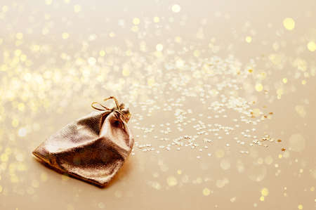 Bag of gold fabric on a background of gold stars. Festive Christmas background. Christmas gifts concept. Close up. Selective focus.の写真素材