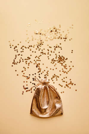 Bag of gold fabric on a background of gold stars. Festive Christmas background. Christmas gifts concept, flat lay.の写真素材