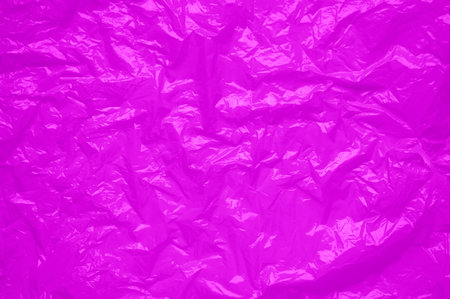 Pink cellophane sheet with shiny crumpled texture. abstract neon background
