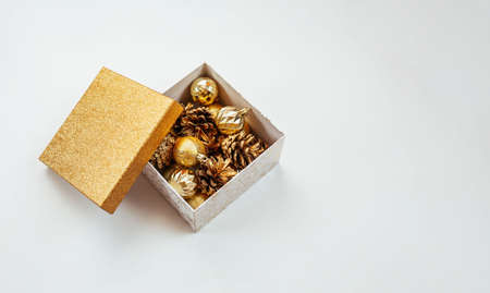 Box with golden christmas decorations on a white background. Golden Christmas balls and fir cones. Christmas background.の写真素材