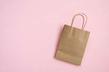 Empty brown paper bag with handles for shopping on a pink background. Copy space. Flat lay.の写真素材
