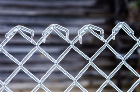 Ice on a fence made of metal mesh. Icy rain in the winter. Atmospheric phenomena of nature. Close up.の写真素材
