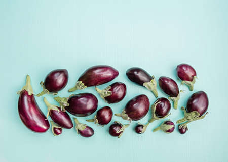 Eggplants of different sizes on a wooden background with mint color. Flat lay. Top view. Copy space.の写真素材