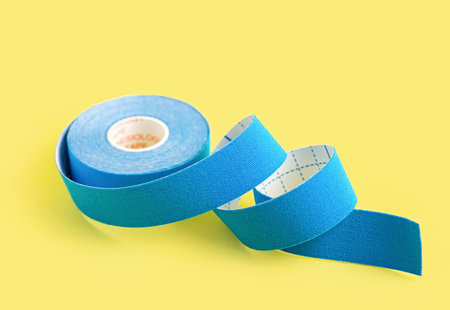 Blue kinesiology tape on a yellow background. Physiotherapy tape to relieve pain and tension....