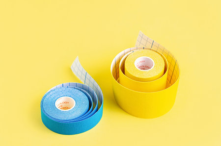 Yellow and blue kinesiology tape on a yellow background. Physiotherapy tape to relieve pain and...