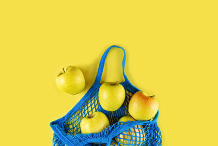 Blue string bag with apples lies on a yellow background. Flat lay.の写真素材