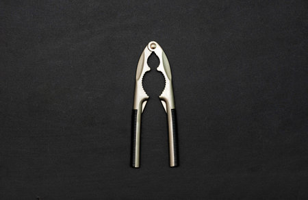 Tool for chopping nuts, nutcracker on a black background. Copy space. Flat lay. Top view. Black...